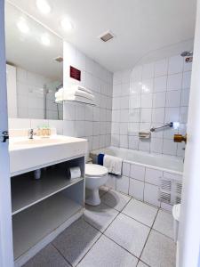 a bathroom with a sink and a toilet and a tub at Tempo Rent Apart Hotel in Santiago