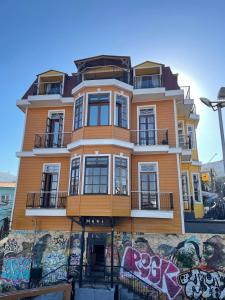 un edificio amarillo con graffiti en el costado en Casa Vander Hotel Boutique en Valparaíso