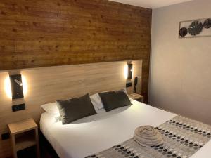 1 dormitorio con cama blanca y pared de madera en Logis Hotel-Restaurant Spa Le Lac, en Embrun