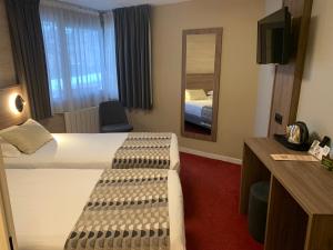 a hotel room with two beds and a mirror at Logis Hotel-Restaurant Spa Le Lac in Embrun