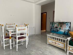 a living room with three white chairs and a tv at Marsa Authentic Luxury Appart 1 in La Marsa