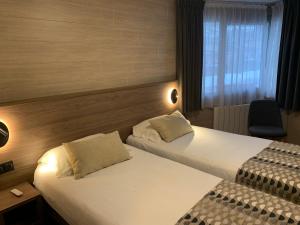 Pokój hotelowy z 2 łóżkami i krzesłem w obiekcie Logis Hotel-Restaurant Spa Le Lac w mieście Embrun