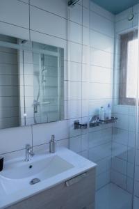 ein weißes Badezimmer mit einem Waschbecken und einem Spiegel in der Unterkunft KASA JURA - Au coeur des monts in Saint-Claude