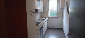 a white kitchen with a sink and a window at Presolana Home in Castione della Presolana