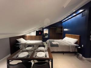una camera d'albergo con due letti e un tavolo con piatti di Loft Dona Clara 204 no coração de Pomerode a Pomerode