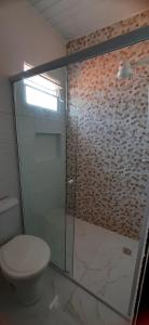 a bathroom with a toilet and a glass shower at Pousada Brilho dos Lençóis in Barreirinhas