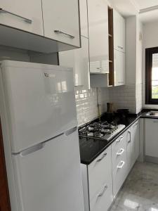 La cuisine est équipée de placards blancs et d'un réfrigérateur blanc. dans l'établissement Marsa Authentic Luxury Appart 1, à La Marsa