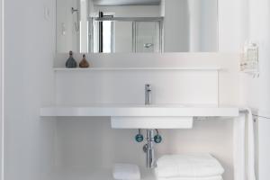 W łazience znajduje się biała umywalka i lustro. w obiekcie Apartamentos Las Torres w Madrycie