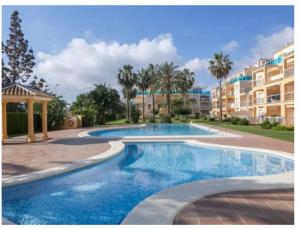- une piscine en face d'un bâtiment avec des palmiers dans l'établissement La Riviera, à Dénia