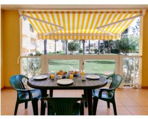 une table à manger avec des chaises et un auvent jaune et blanc dans l'établissement La Riviera, à Dénia