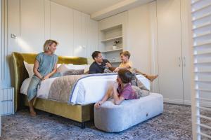 een gezin zittend op bedden in een slaapkamer bij VIZUALIZA Residence Hotel in Plovdiv