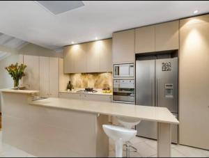 a kitchen with white cabinets and stainless steel appliances at Luxury Retreat Home - 4bed House w/Parking - Mins from CBD in Sydney