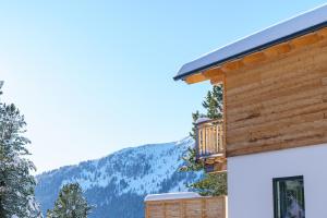 a log cabin with a balcony and mountains in the background at Turrach Chalet´s Grünsee in Turracher Hohe