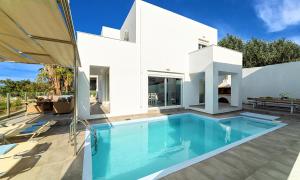 a white house with a swimming pool in front of it at Cretan Sunset Villa Heated Pool in Dhrámia