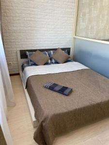 ein Bett mit einer braunen Decke und Kissen darauf in der Unterkunft 1 комнатная квартира в элитном ЖК Альтаир со всеми удобствами in Aqtöbe