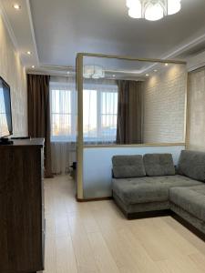 ein Wohnzimmer mit einem Sofa und einem großen Spiegel in der Unterkunft 1 комнатная квартира в элитном ЖК Альтаир со всеми удобствами in Aqtöbe