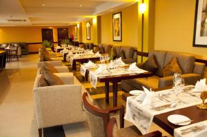 a dining room with tables and couches and chairs at Gorillas Golf Hotel in Kigali