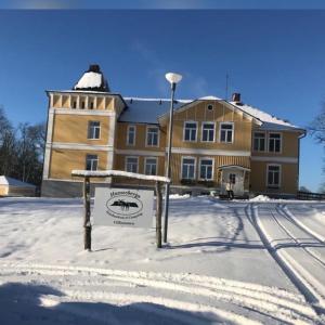 un grand bâtiment avec un panneau dans la neige dans l'établissement Hunnebergs Gård Hostel & Camping, à Vargön