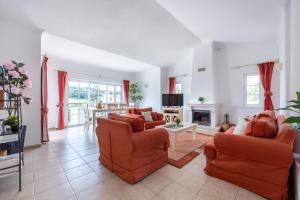 a living room with orange chairs and a fireplace at Casa Ensolarada in Budens