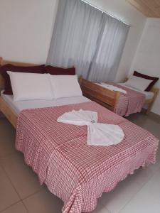 two beds in a room with a red and white blanket at Edicula Fundos in Jordãozinho