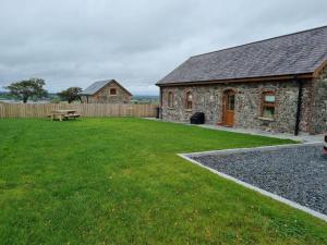 - un bâtiment en pierre avec une table de pique-nique dans une cour dans l'établissement Drumnavaddy Cottage, à Dromore