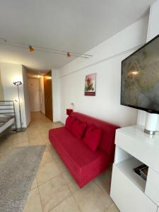 een rode bank in een woonkamer met een flatscreen-tv bij Hotelturm in Augsburg