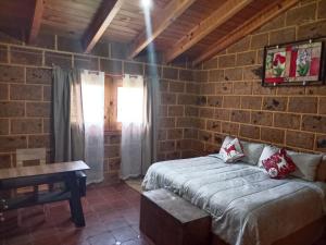 1 dormitorio con 1 cama en una pared de ladrillo en Cabaña el piñon en Ezequiel Montes, en Ezequiel Montes