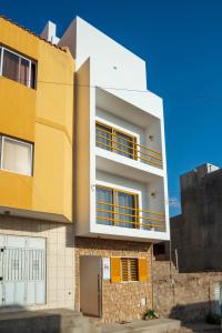 a building with yellow and white at Amwilla Guesthouse Apartamento Fátima in Mindelo