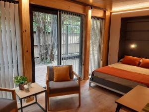1 dormitorio con 1 cama, 1 silla y 1 ventana en Monoambiente cálido y modernoso con amplio jardín en el centro de SMA. 2V5 en San Martín de los Andes