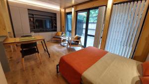 1 dormitorio con cama, escritorio y mesa en Monoambiente cálido y modernoso con amplio jardín en el centro de SMA. 2V5 en San Martín de los Andes
