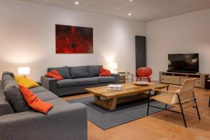 a living room with two couches and a table and a tv at Gîte Bellene Villa de vos Rêves in Beaune