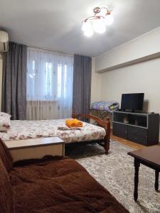 uma sala de estar com duas camas e uma televisão em X,ata 2 em Almaty