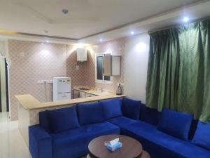 a living room with a blue couch and a kitchen at برج الياسمين 2 in Riyadh