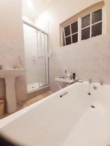 a white bathroom with a tub and a sink at Rehoboth Guesthouse in Durban