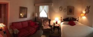 Franklin Terrace Bed and Breakfast في فرانكلين: غرفة نوم بسرير واريكة حمراء