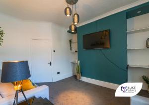 a living room with a blue wall with a tv at Luke Stays - Brighton Road in Gateshead
