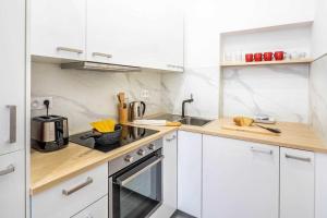 a white kitchen with a sink and a stove at Cosy Studio in the heart of Belleville in Paris
