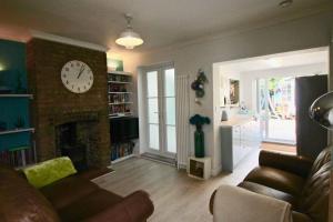 een woonkamer met een klok op een bakstenen open haard bij Pebbles in Deal