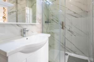 biała łazienka z umywalką i prysznicem w obiekcie Cosy flat in the heart of Belleville w Paryżu