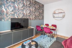 a living room with a tv and a table with chairs at Cosy flat in the heart of Belleville in Paris