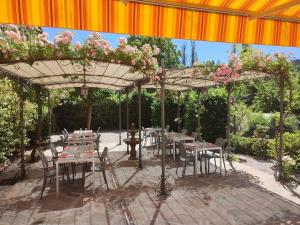 a patio with tables and chairs under an umbrella at Le Relais de Ceilhes in Ceilhes-et-Rocozels