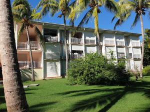 a building with palm trees in front of it at Escapades ensoleillees - Saint-Francois - Front de Mer et Piscine in Saint-François