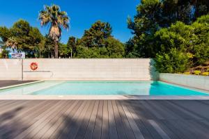 uma piscina com cerca e árvores em Santo Amaro Beach Apartment em Oeiras