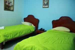AguadulceにあるHotel Interamericanoの青い壁のベッドルーム1室(ベッド2台、緑のシーツ付)