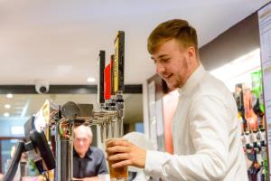 a man standing at a bar with a glass of beer at Daish's Blackpool Hotel in Blackpool