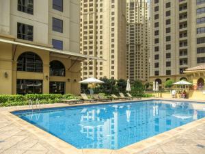 a large swimming pool in a building with tall buildings at Alluring 2-BR APT Near Beach at Sadaf 1 with Marina View in Dubai