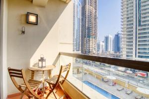 een balkon met een tafel en stoelen en uitzicht op de stad bij Alluring 2-BR APT Near Beach at Sadaf 1 with Marina View in Dubai