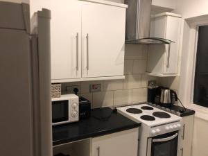 a kitchen with white cabinets and a stove and a microwave at Clapham 1 in London +8 photos