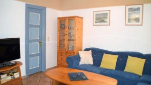 uma sala de estar com um sofá azul e uma mesa em Haus 94- Whg 2 em Oldsum