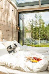 a bed with a plate of fruit on it at Kuuru Tunturilaakso by Kide Hotel in Syöte